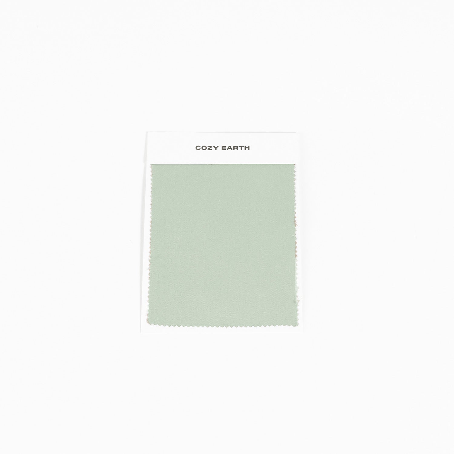 A laurel-colored Bamboo Sheet Swatch with zigzag edges is attached to a white card labeled "Cozy Earth," set against a plain white background.