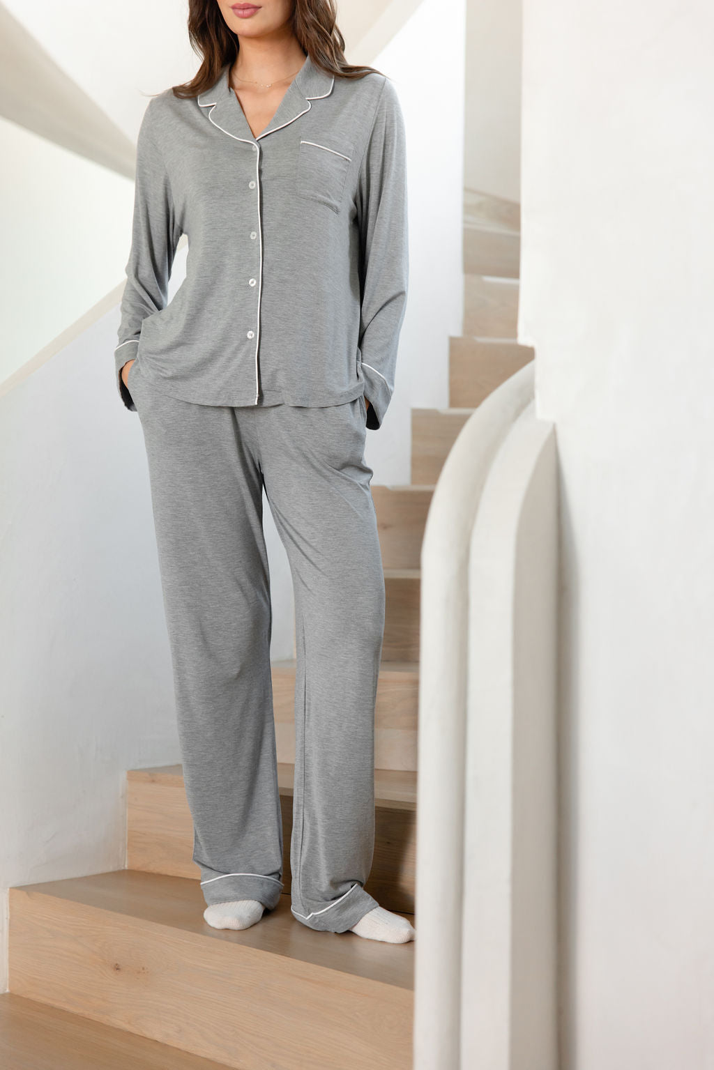 Woman standing on stairs wearing grey pajama set 