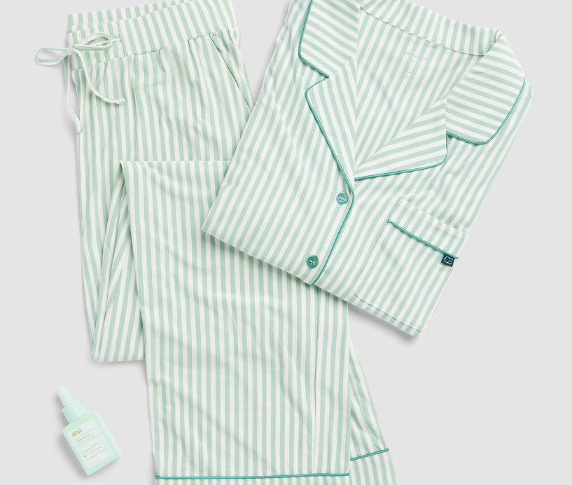 Green and white striped pajama set with a small bottle on a light gray background