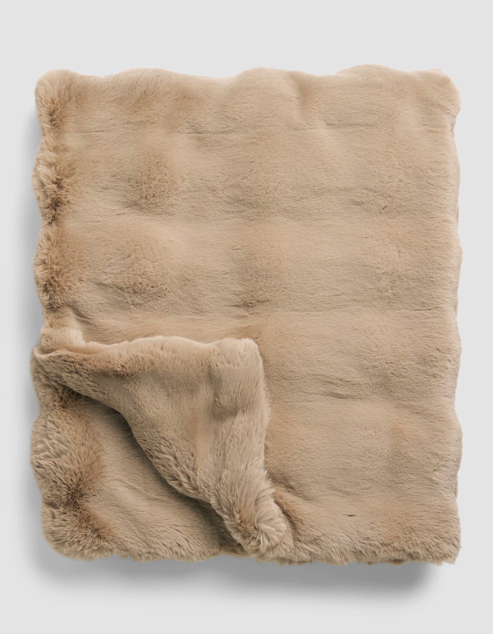The Cozy Earth Double Bubble Cuddle Blanket is neatly folded, featuring soft, beige faux fur with one corner turned up to display its plush, fluffy underside.