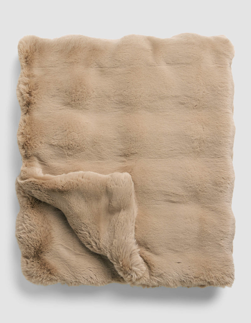 The Cozy Earth Double Bubble Cuddle Blanket is neatly folded, featuring soft, beige faux fur with one corner turned up to display its plush, fluffy underside.