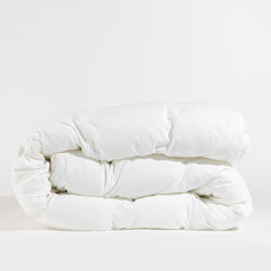 A neatly folded Down Alternative Comforter by Cozy Earth is placed against a plain background. The quilted texture is visible, highlighting its fluffy and soft appearance.