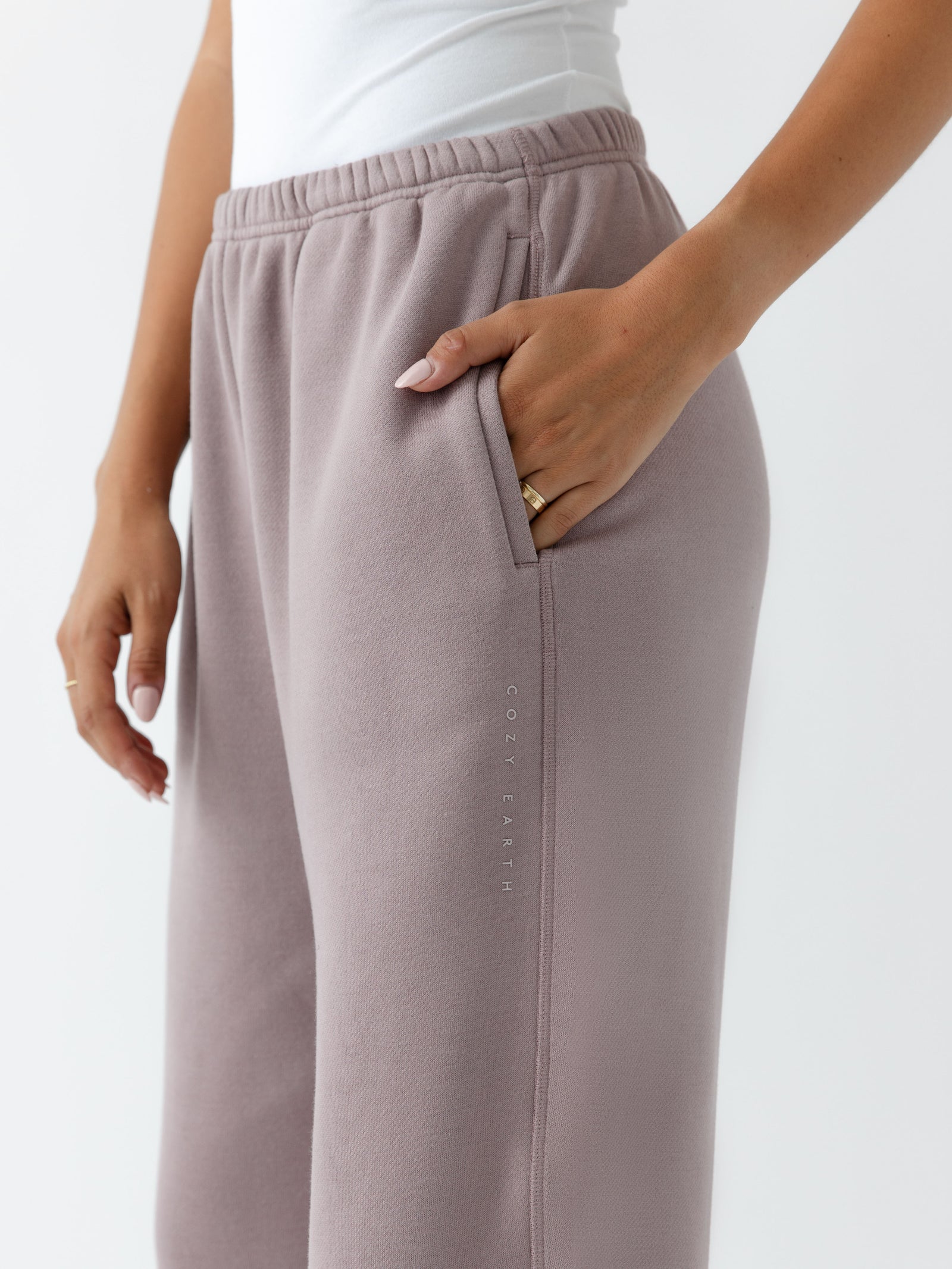 Dusty Orchid CityScape Joggers. The Joggers are being worn by a female model. The photo is taken from the waist down with the models hand in the pocket of the joggers. The back ground is white. 