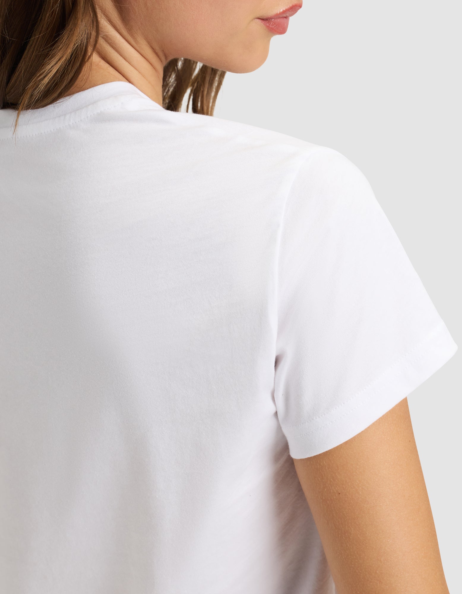 A woman wears the Cozy Earth Women's Easy Tee, shown from the back and slightly to the side, with part of her face, neck, and shoulder visible against a plain light background. 