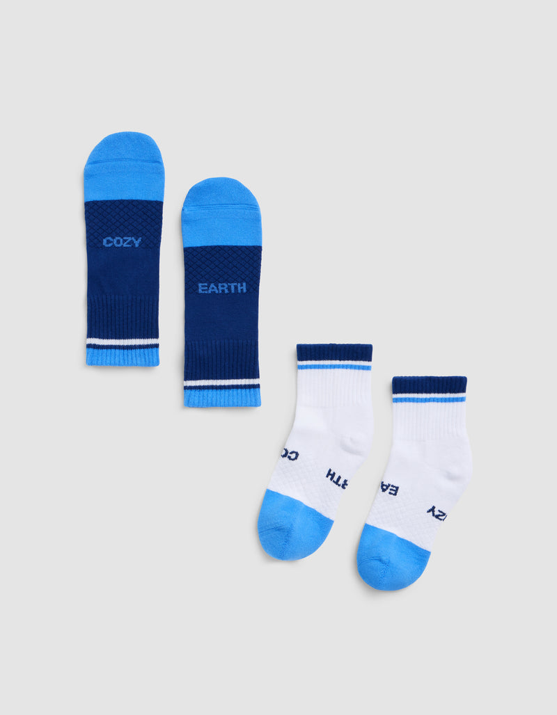 Two pairs of Cozy Earth Essential Quarter Socks are shown: one pair in dark blue with "COZY" and "EARTH" on the soles, and one pair in white with blue toes, heels, cuffs, and "COZY" and "EARTH" on the soles.