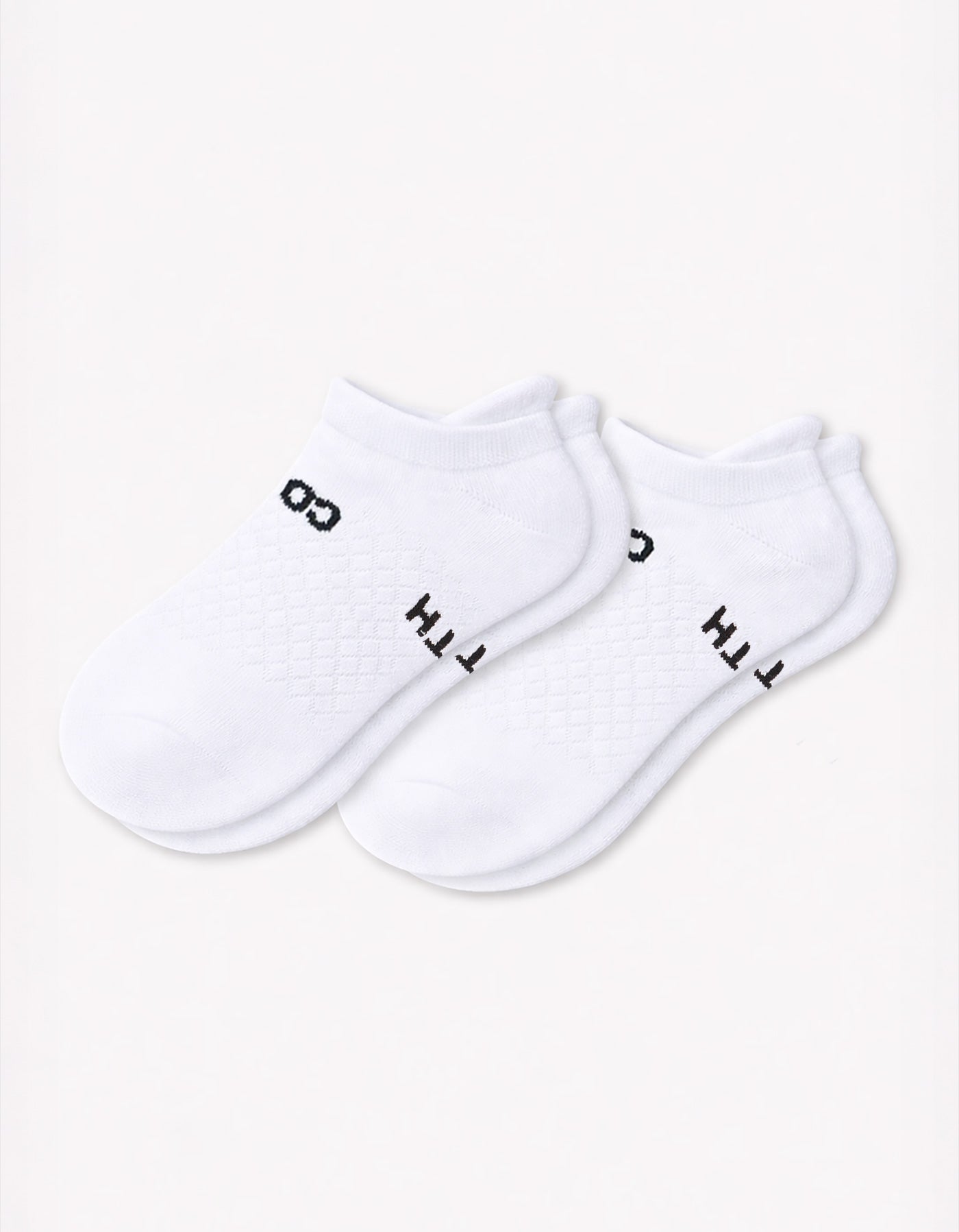 The Cozy Earth Women's Essential Ankle Sock in white is shown on a plain white background, featuring partially visible black lettering on each sock.|Color:White