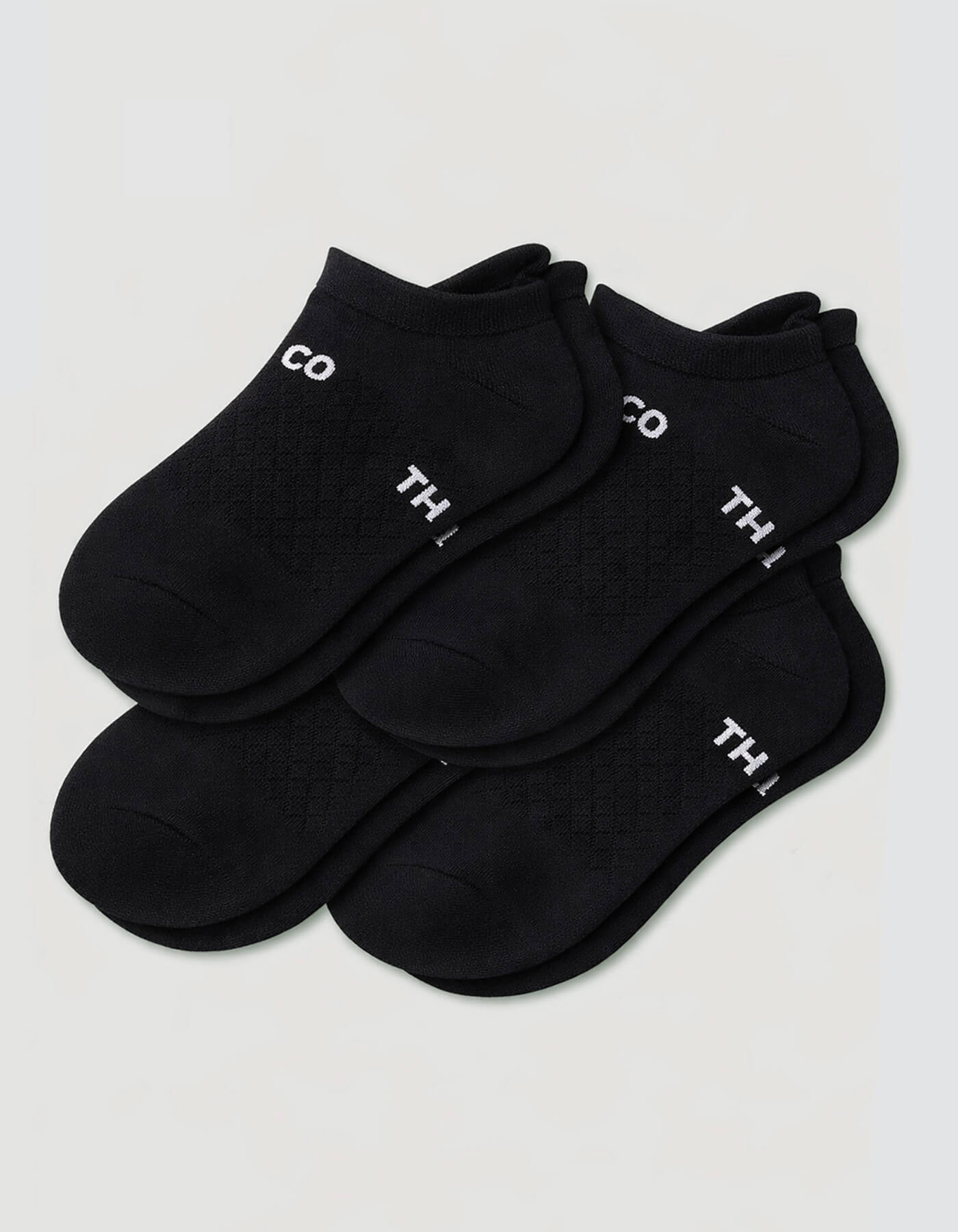 Four pairs of black Women's Essential Ankle Socks by Cozy Earth, featuring a textured pattern and partial white text near the cuffs, displayed on a light gray background.