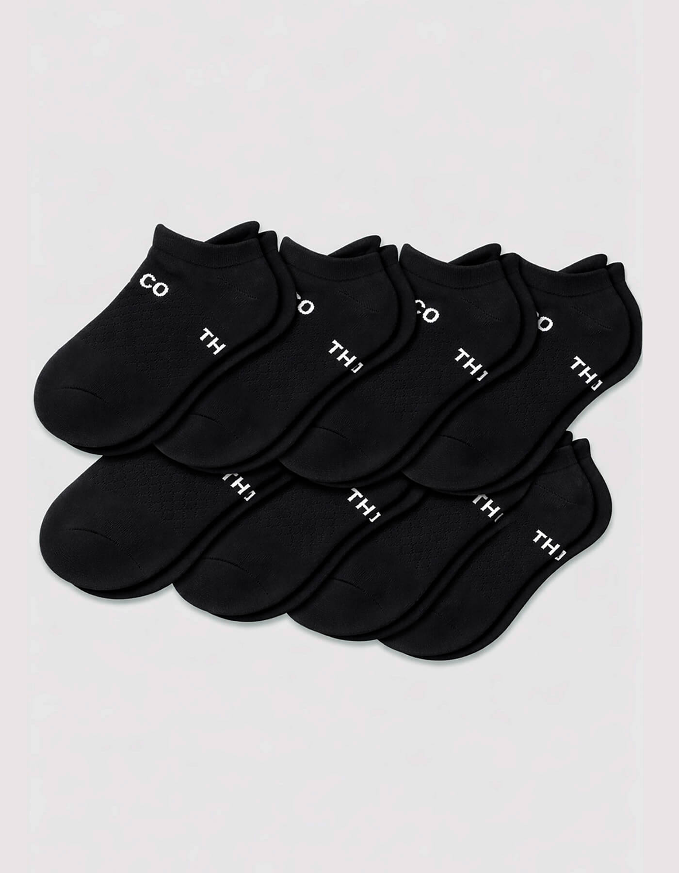 Eight pairs of Cozy Earth Men's Essential Ankle Socks in black are neatly arranged on a light gray background, each featuring small white text near the cuff.