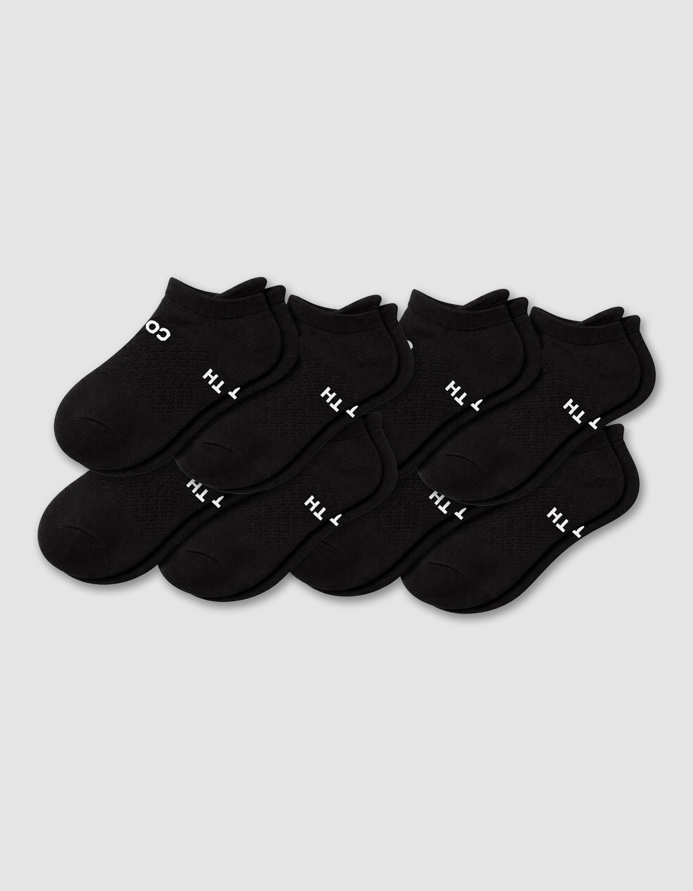 Eight pairs of Cozy Earth Men's Essential ankle socks in black are arranged in two rows on a plain light gray background, with some showing white text near the cuff.|Color:Black