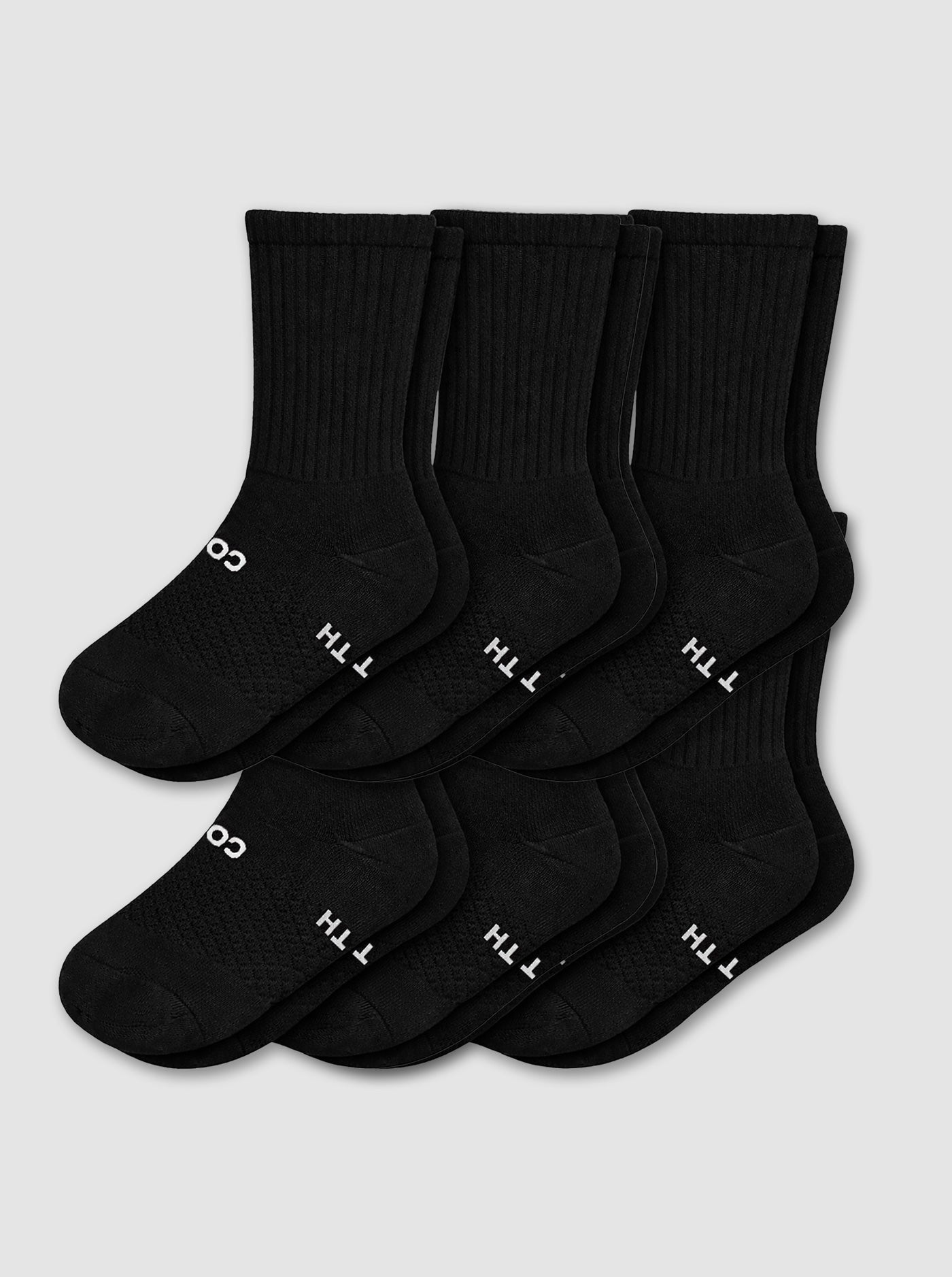 Six pairs of black Women's Essential Calf Socks by Cozy Earth are neatly overlapped with "COTTON" partially visible in white on the soles, displayed against a light gray background.