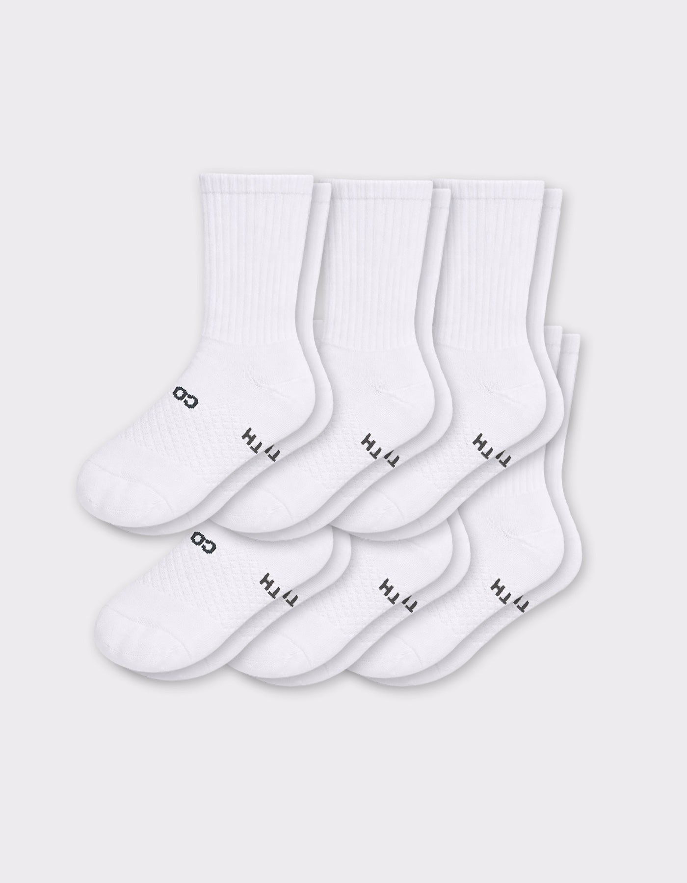 Six pairs of Cozy Earth Men's Essential Calf Socks in white are arranged in two rows on a light gray background, each featuring small black text and a symbol near the toes and ribbed cuffs.