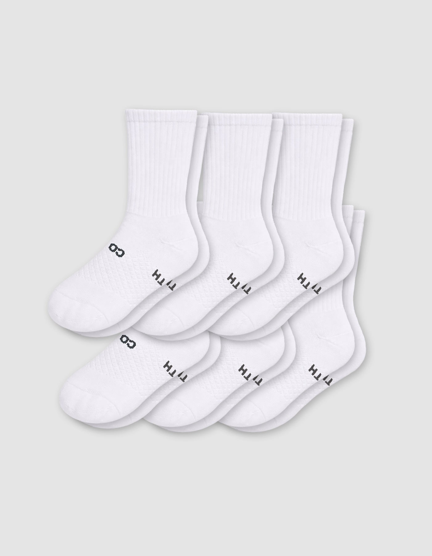Six pairs of Cozy Earth Men's Essential Calf Socks in white are arranged in two rows on a light gray background, each featuring small black text and a symbol near the toes and ribbed cuffs.