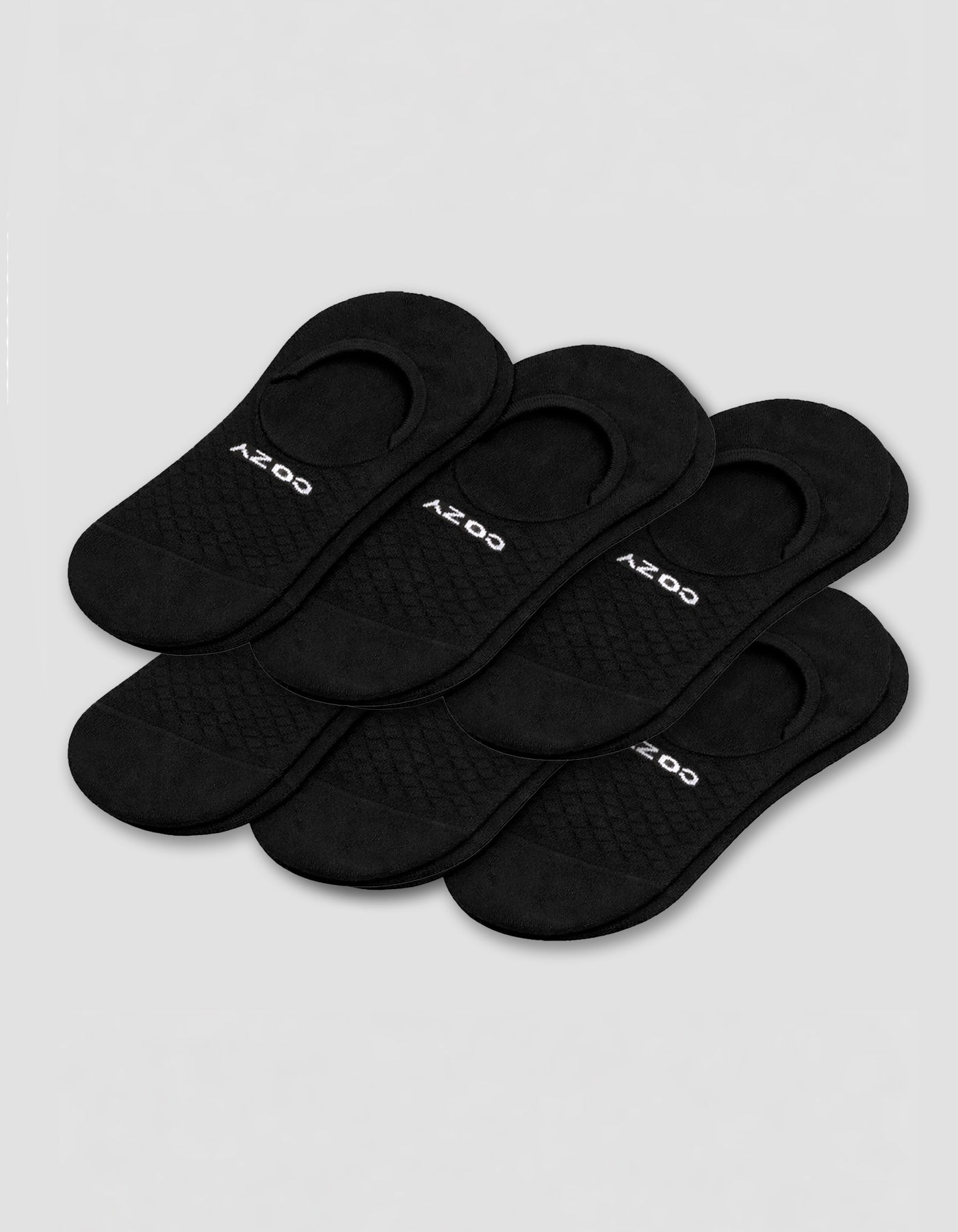 Six pairs of black Cozy Earth Men's Essential No-Show Socks are stacked on a plain white background, each featuring "COZY" printed in white near the heel opening.