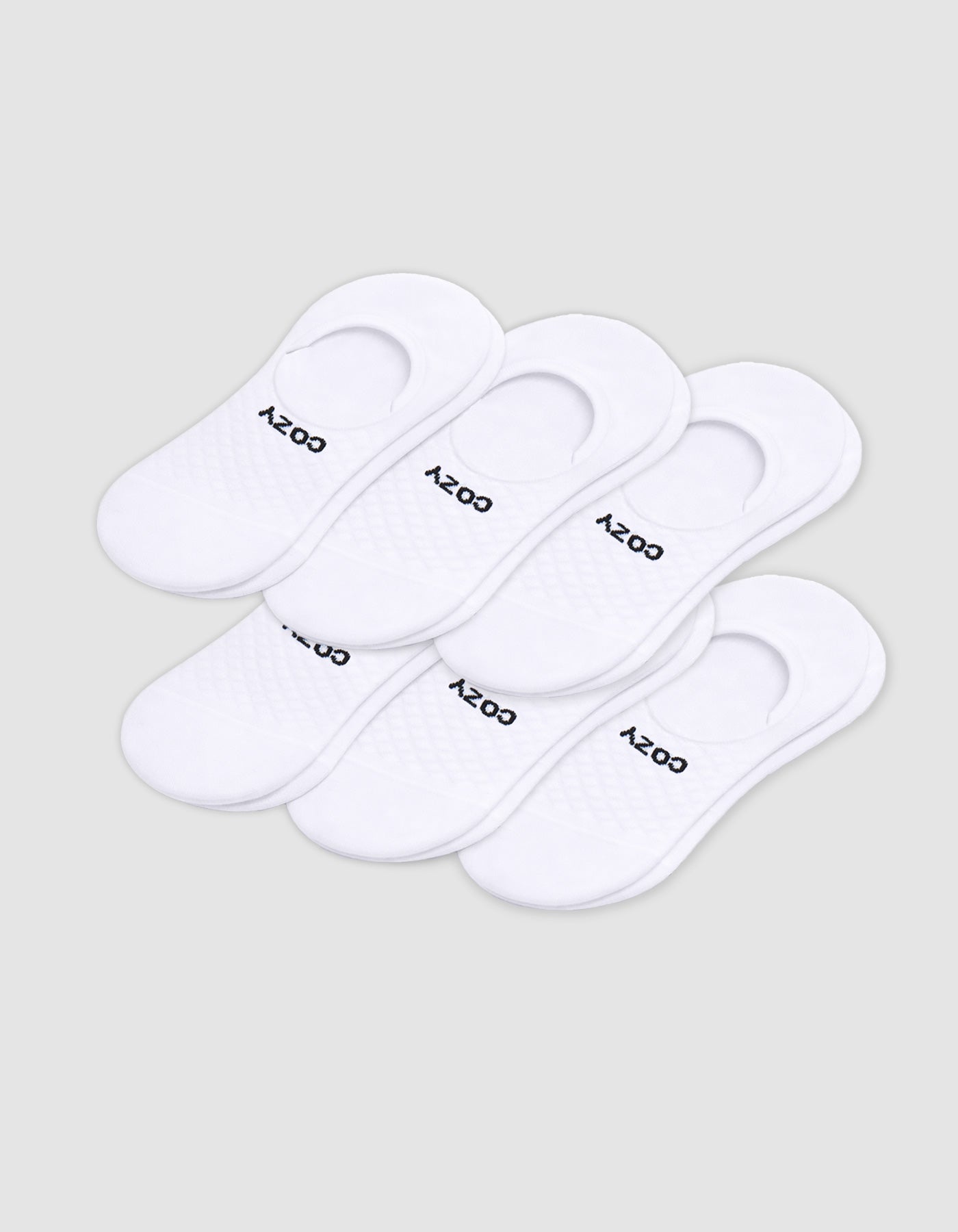 Six pairs of Cozy Earth Men's Essential No-Show Socks are stacked on a plain white background, each featuring "COZY" printed in black near the heel opening.|Color:White