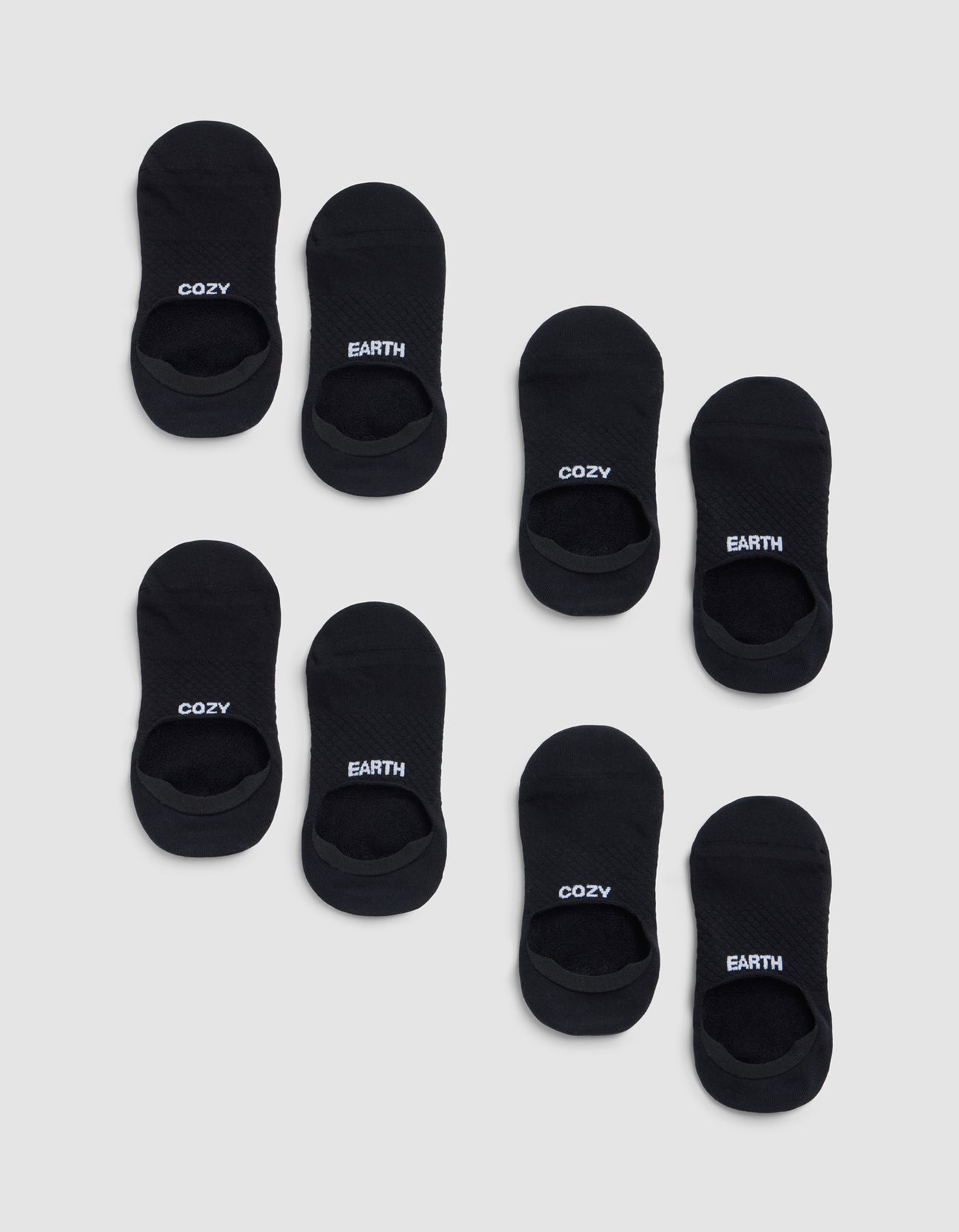 Eight pairs of black Essential No-Show Socks from Cozy Earth on a light gray background—four pairs read "COZY" and four read "EARTH" in white lettering on top. 