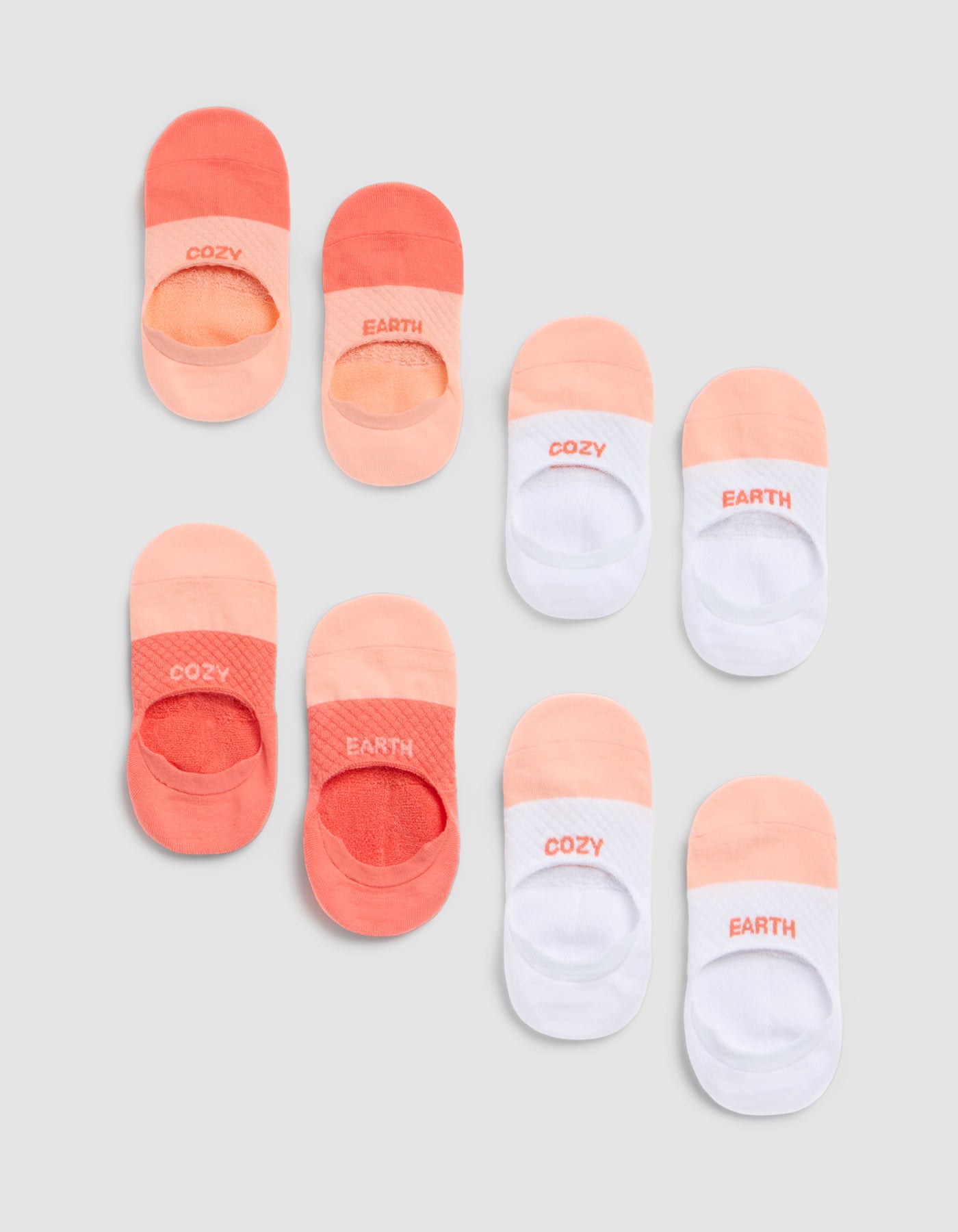 The Cozy Earth Essential No-Show Sock 4-Pack includes socks in peach, orange, and white tones with "COZY" or "EARTH" printed on the toes, shown arranged neatly on a light grey background. |Color:Canteloupe