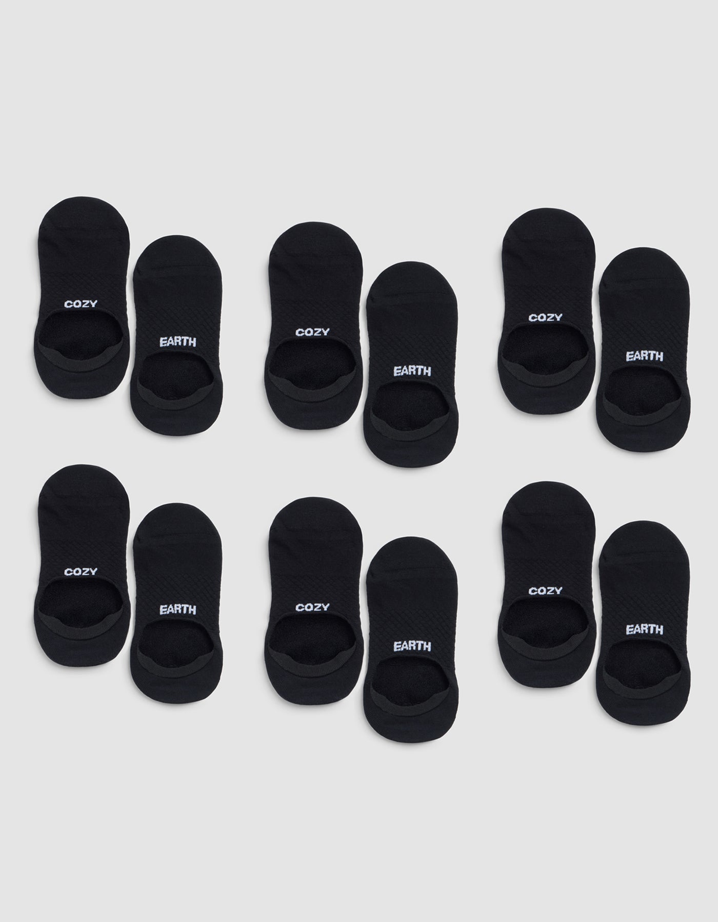 Six pairs of black Essential No-Show Socks by Cozy Earth are arranged in four rows on a light gray background, each labeled "COZY" or "EARTH" near the opening. 