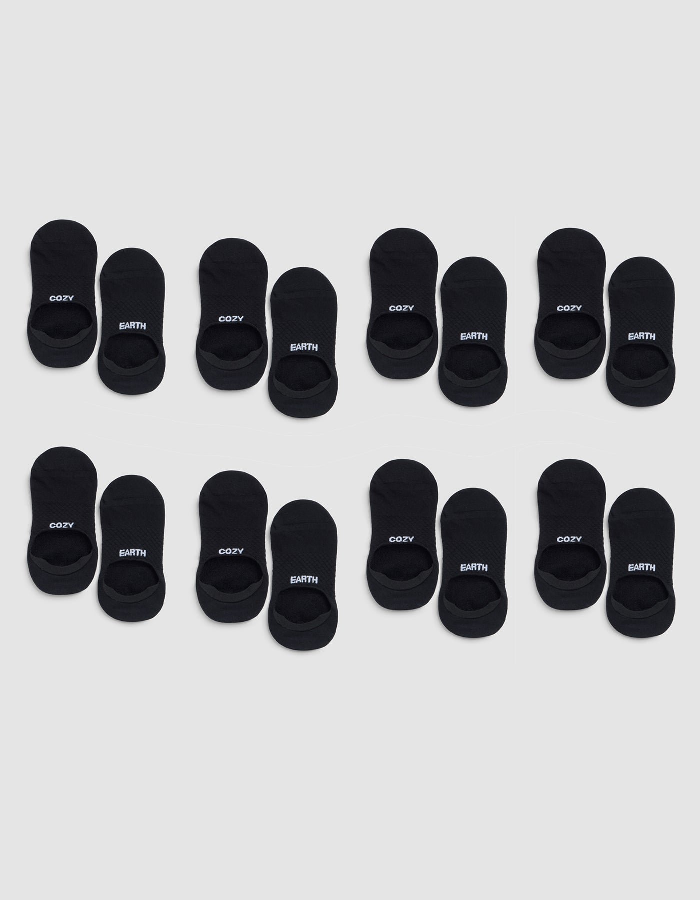 Eight pairs of Cozy Earth Essential No-Show Socks are arranged in three rows on a light gray background, with "COZY" and "EARTH" printed in white letters on the black socks. |Color:Black