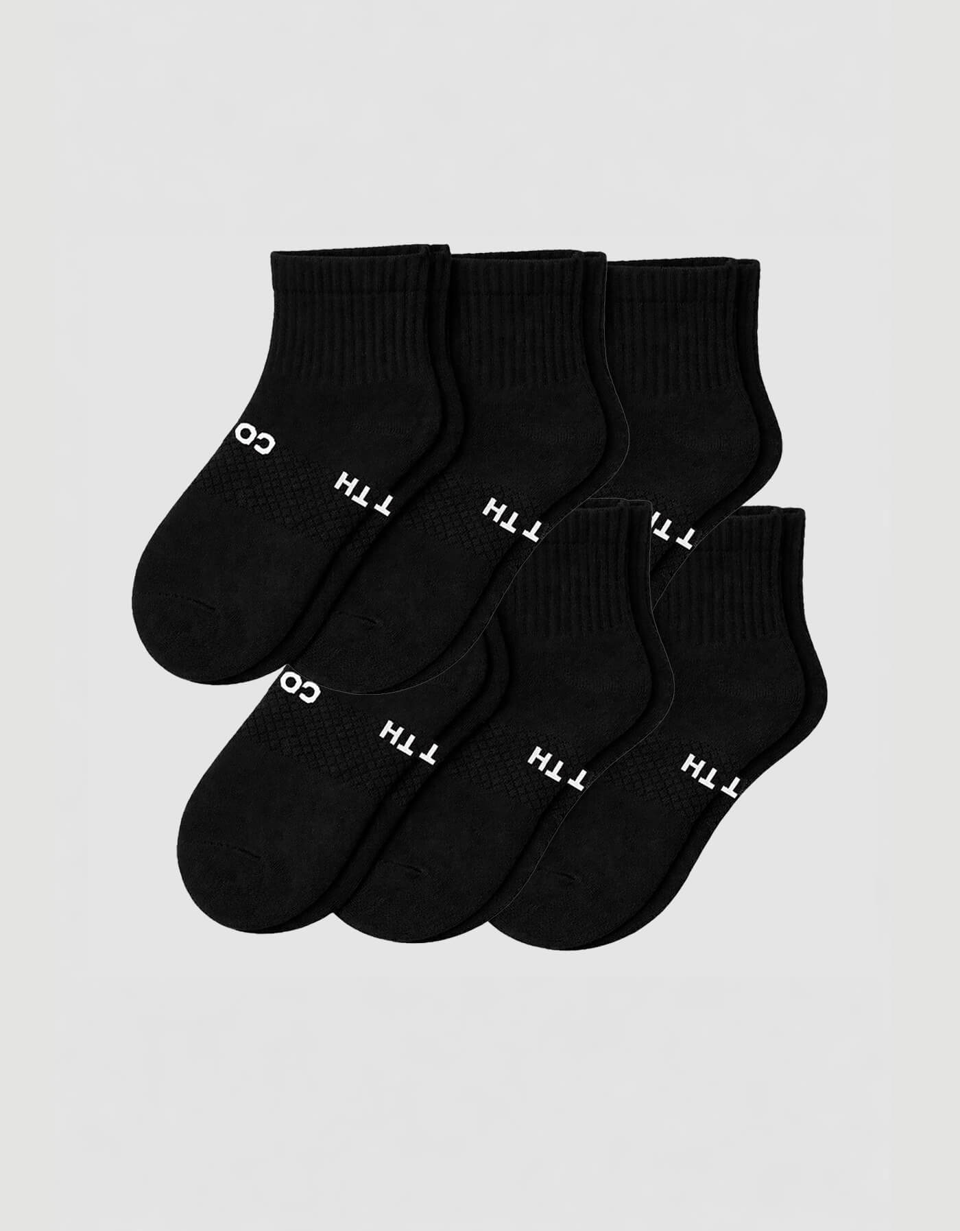 Six pairs of Cozy Earth Men’s Essential Quarter Socks in black are neatly displayed on a plain background, each featuring a ribbed cuff and white text by the toes. 