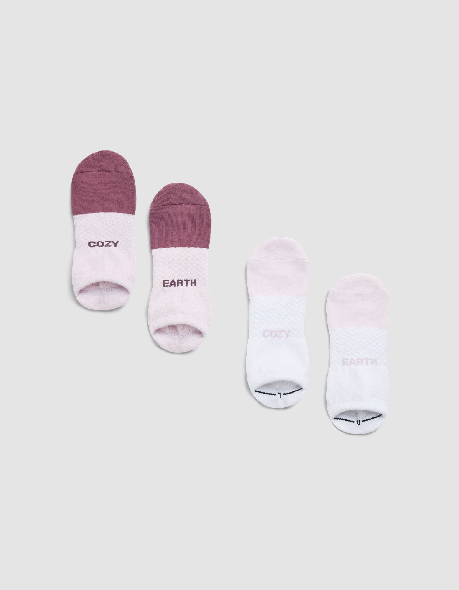 Four pairs of Cozy Earth Essential Ankle Socks are displayed on a light background: pink and purple on the left with "COZY" and "EARTH," and light pink and white on the right featuring a small graphic and faint toe text. 