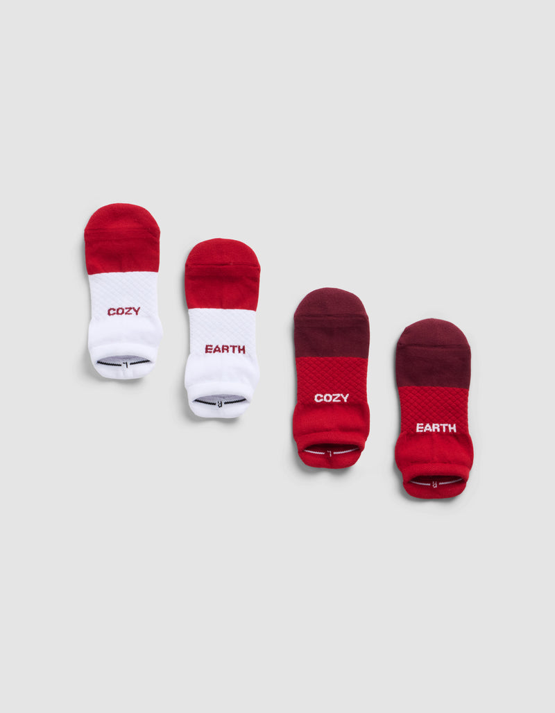 Four Cozy Earth Essential Ankle Socks are displayed side by side on a light gray background: two are red and white with "COZY," and two are red and maroon with "COZY" and "EARTH" written on them.