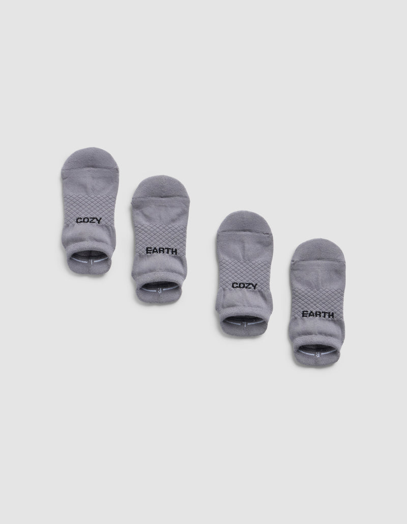 Four small gray Essential Ankle Socks by Cozy Earth are arranged in two pairs on a white background. The left pair has "COZY" and the right pair has "EARTH" printed in black text near the cuff.