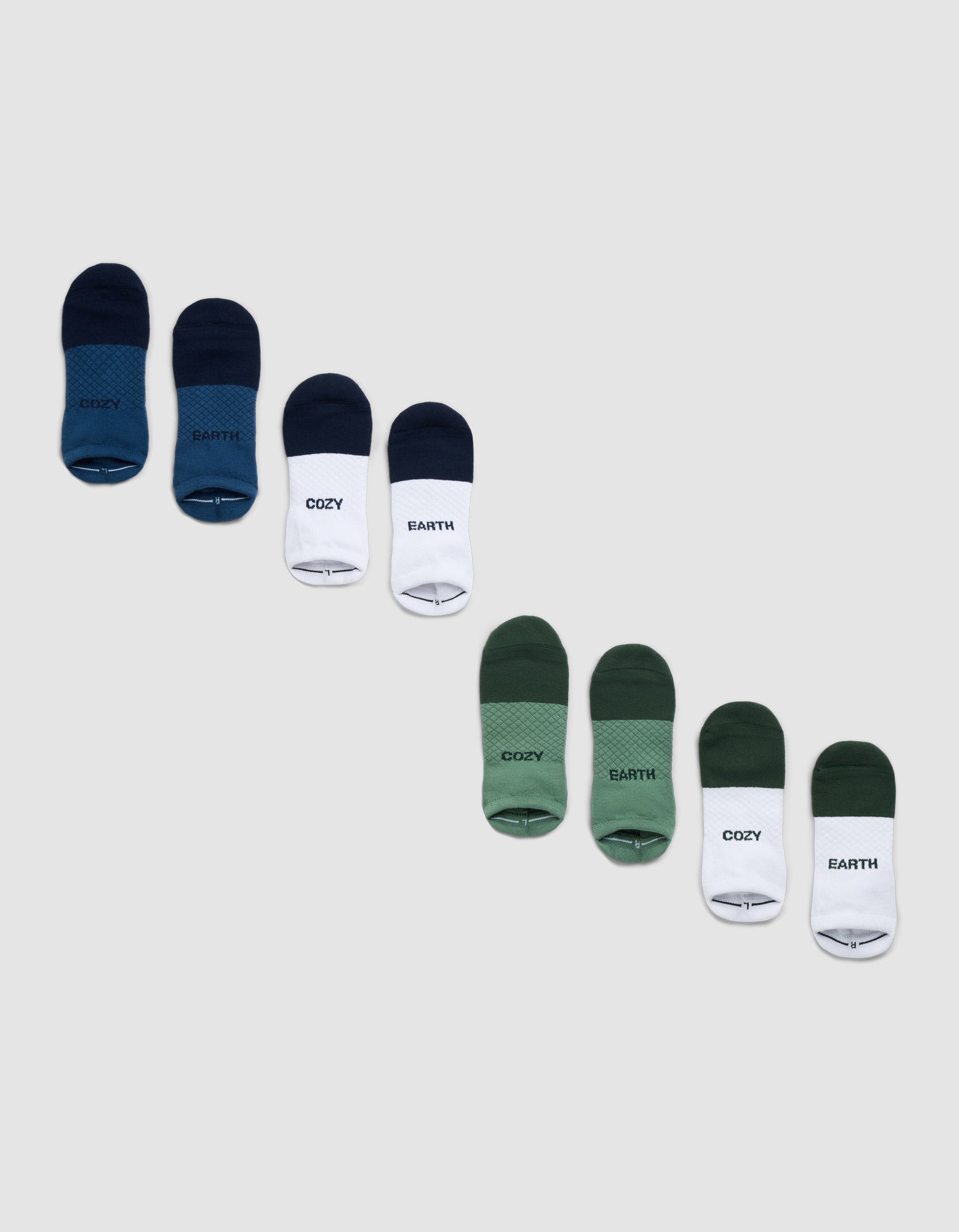 The Cozy Earth Essential Ankle Sock 4-Pack includes green, blue, and white socks, some featuring "COZY" or "EARTH" text, arranged diagonally on a light gray background. 