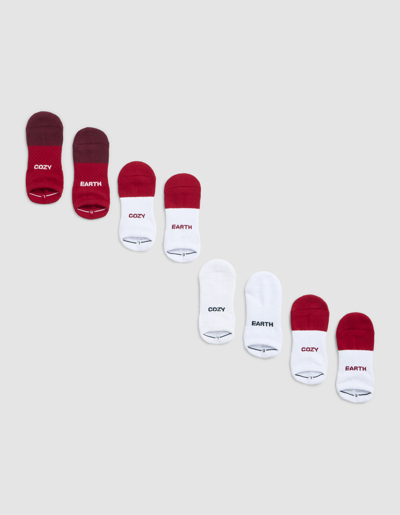 Eight pairs of Cozy Earth Essential Ankle Sock 4-Packs in red and white, arranged diagonally on a light grey background. Some socks feature "COZY" or "EARTH" labels.