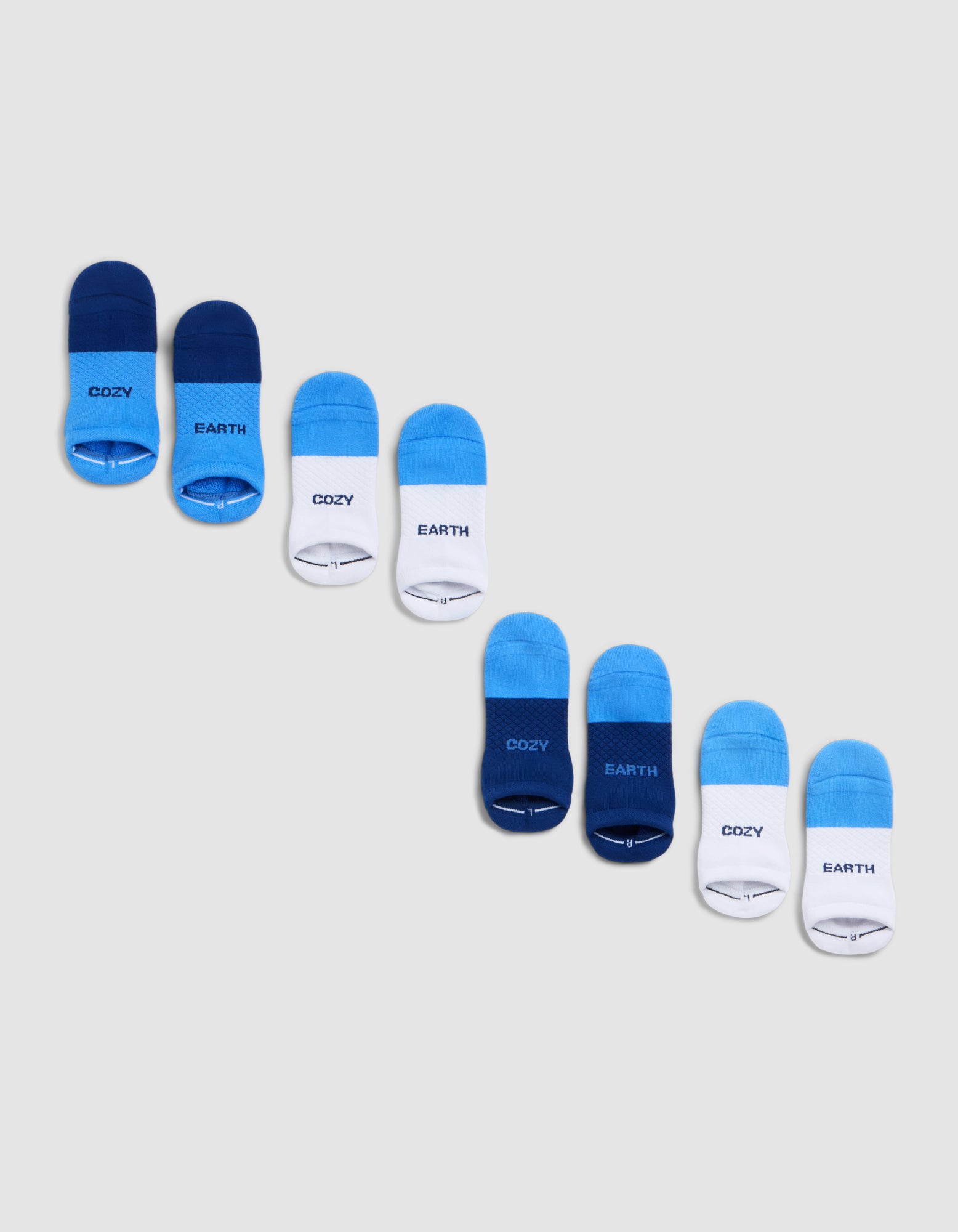 The Cozy Earth Essential Ankle Sock 4-Pack includes eight pairs, arranged diagonally in dark blue, bright blue, and white. Some have "COZY" or "EARTH" printed near the toes. 