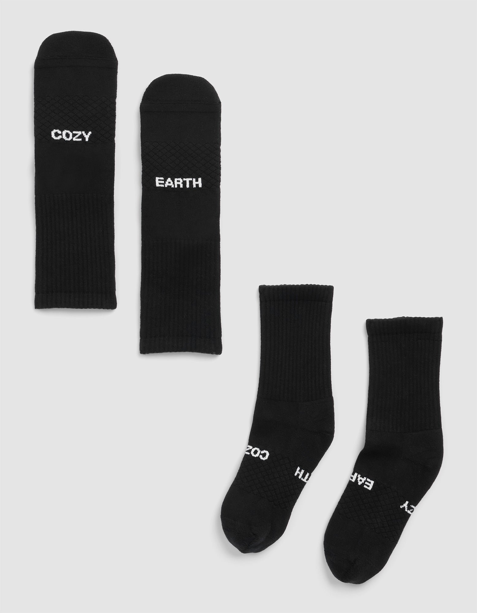 Four Essential Calf Socks by Cozy Earth in black are on a light background—two laid flat display "COZY" and "EARTH" in white, while two others are side by side with partial text visible. |Color:Black