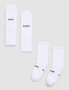 Four Essential Calf Socks by Cozy Earth are displayed on a light gray surface. Each white ribbed sock features black text: two say "COZY," and two say "EARTH." The socks are arranged flat and side by side. |Color:White