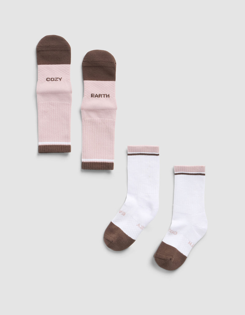 The Essential Calf Sock by Cozy Earth includes a pink and brown pair with “COZY” and “EARTH” on them, plus a white pair with pink trim and brown toes and heels, both shown on a light gray background.