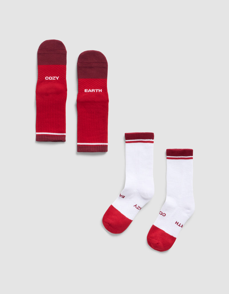 Four Cozy Earth Essential Calf Socks are shown: two red with “COZY” and “EARTH” in white, and two white with red toes/heels and the same lettering. All lie flat on a light gray background.