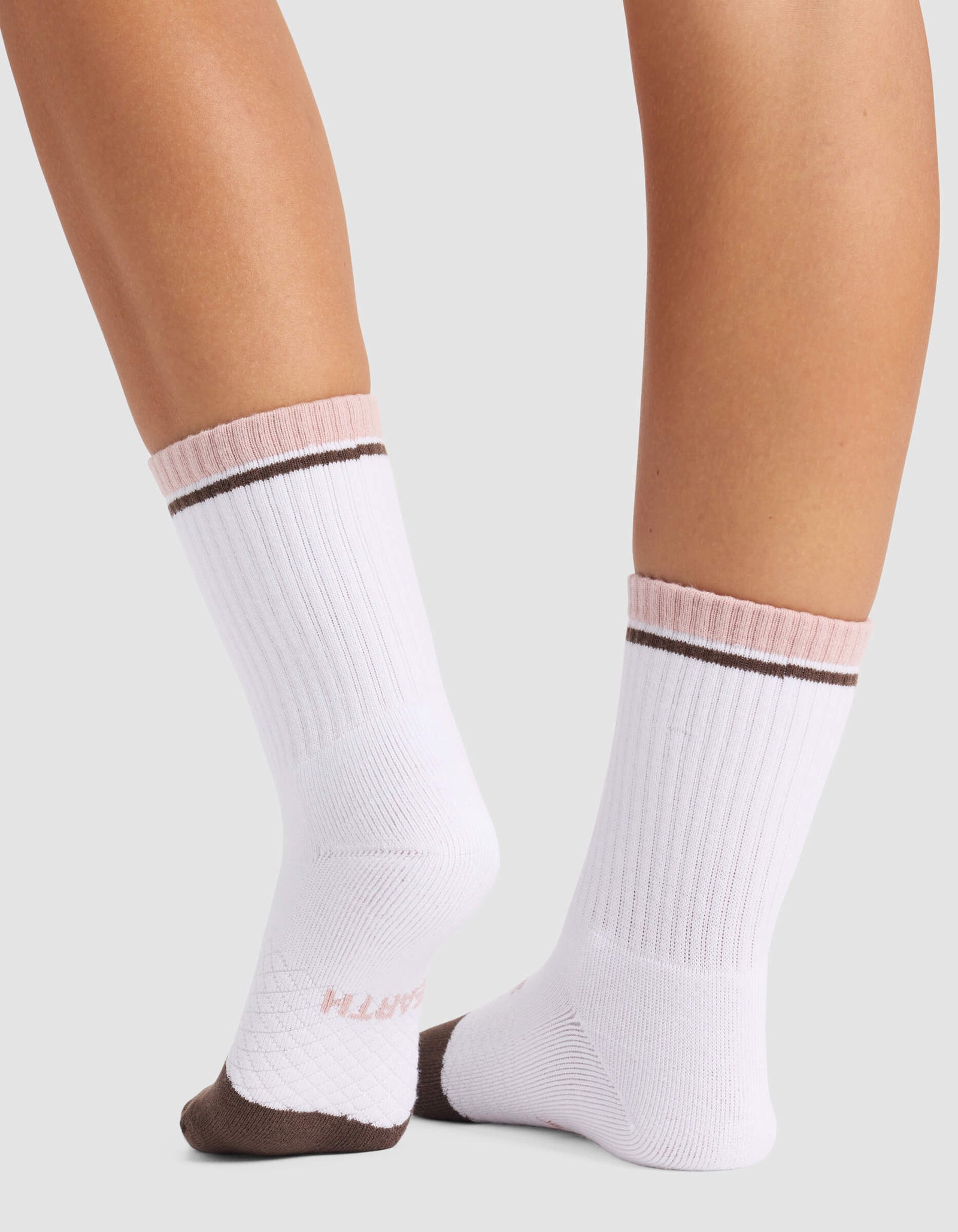 A close-up of lower legs wearing Cozy Earth Women's Essential Calf Socks—white with pink cuffs, brown stripes near the top, brown toes, and "SMITH" in pink on the sole.