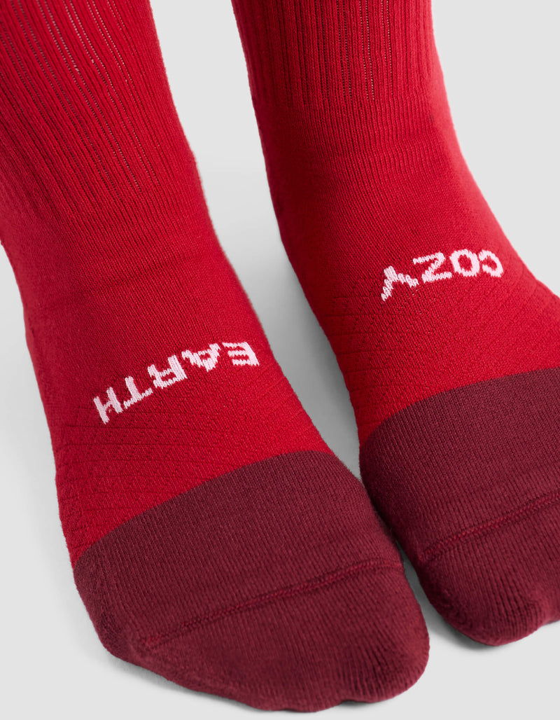 Close-up of feet wearing Cozy Earth Women's Essential Calf Socks in red with darker red toes. "EARTH" is printed on the left sock and "COZY" on the right, both in white text near the toes.
