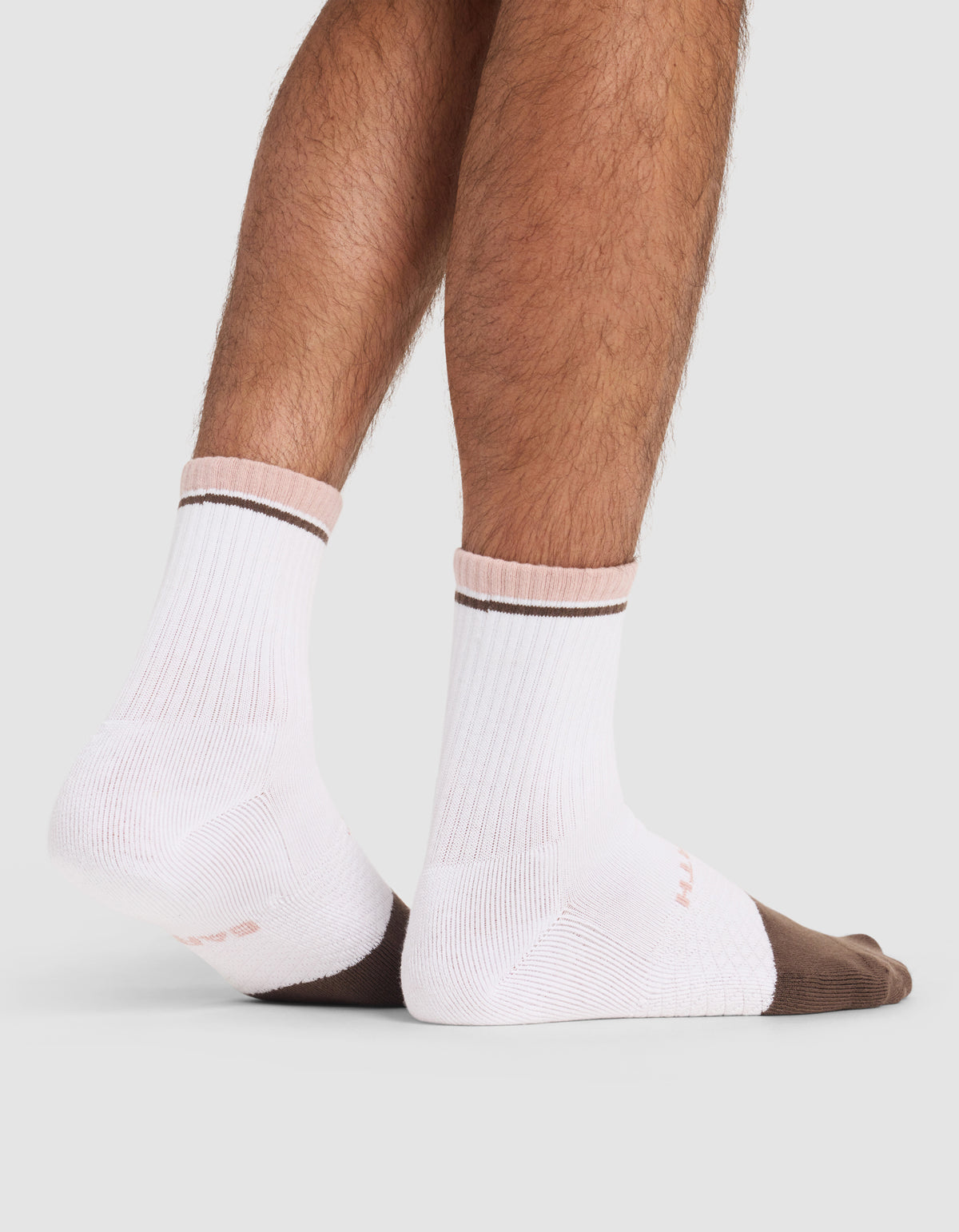 A person wearing Cozy Earth Essential Calf Sock (white with brown toes and a thin brown stripe) stands on a light gray surface, showing only their lower legs and feet.