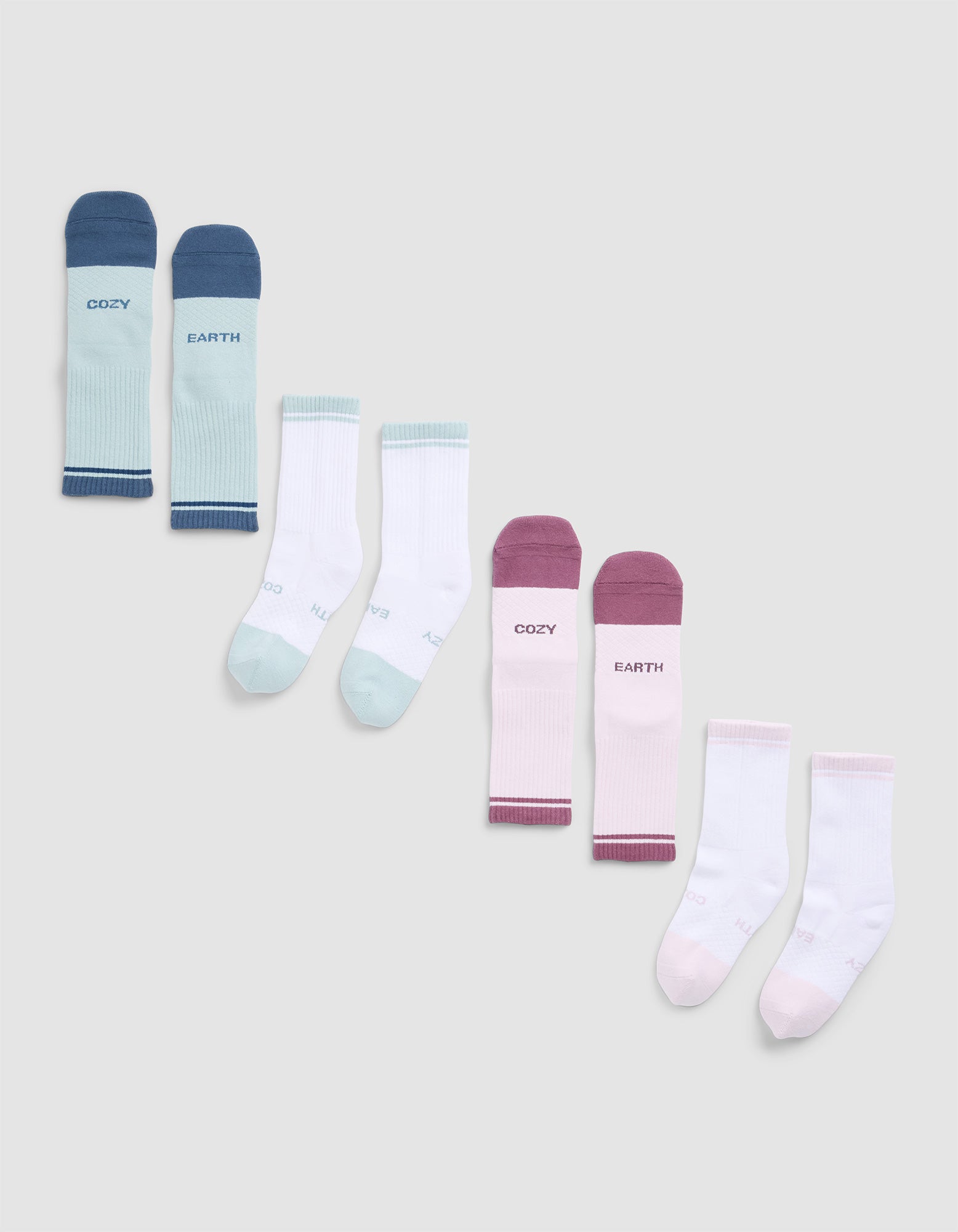 Four pairs of Cozy Earth Essential Calf Socks in blue, mint green, burgundy, and light pink—each featuring text on the tops—are arranged in a row on a light grey background.