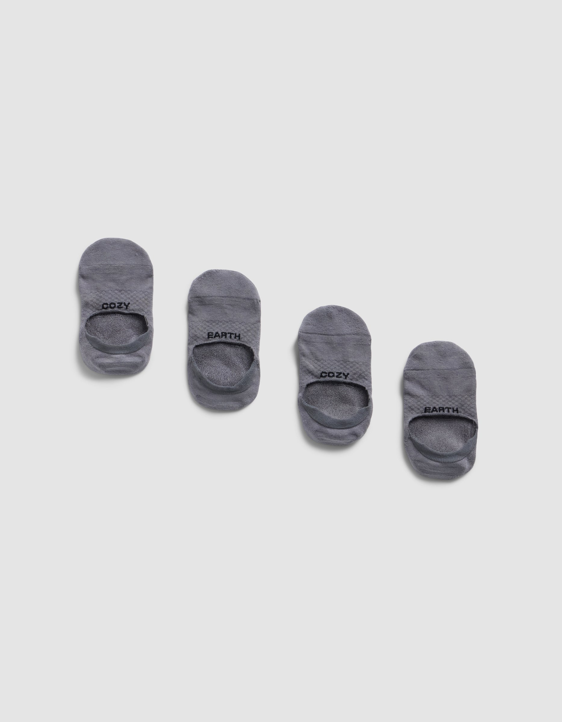 Four pairs of Cozy Earth Essential No-Show Socks are arranged in a row on a light gray background, each displaying "COZY EARTH" in black text near the opening.|Color:Stone