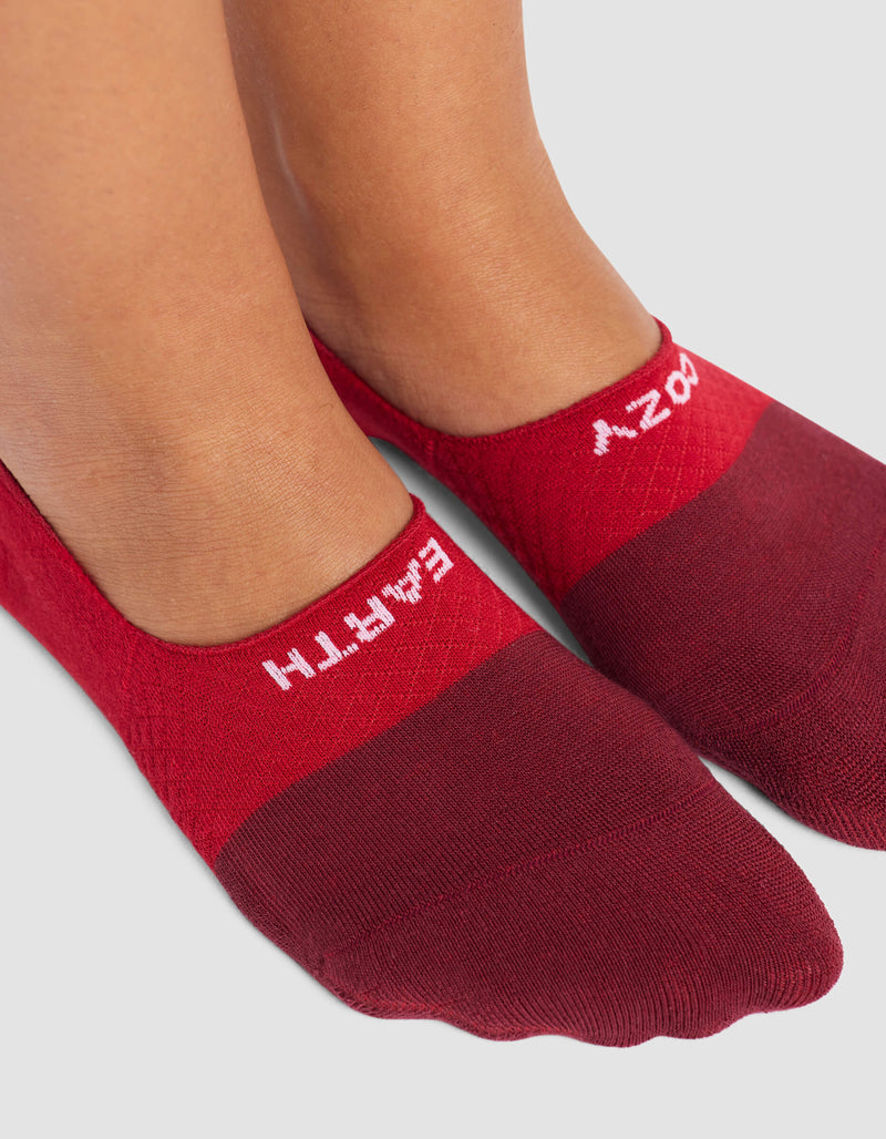 A close-up shows feet in Cozy Earth Women's Essential No-Show Socks, red with "EMPATHY" in white near the top edge, against a light gray background.