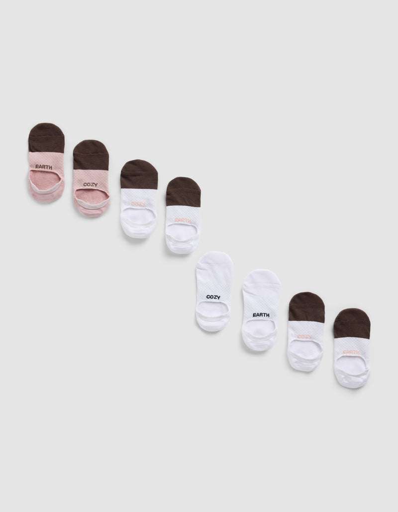 Four packs of Essential No-Show Socks by Cozy Earth are arranged diagonally on a light background, showcasing pink, brown, and white colors. Some socks feature the labels "COZY" or "EARTHY.
