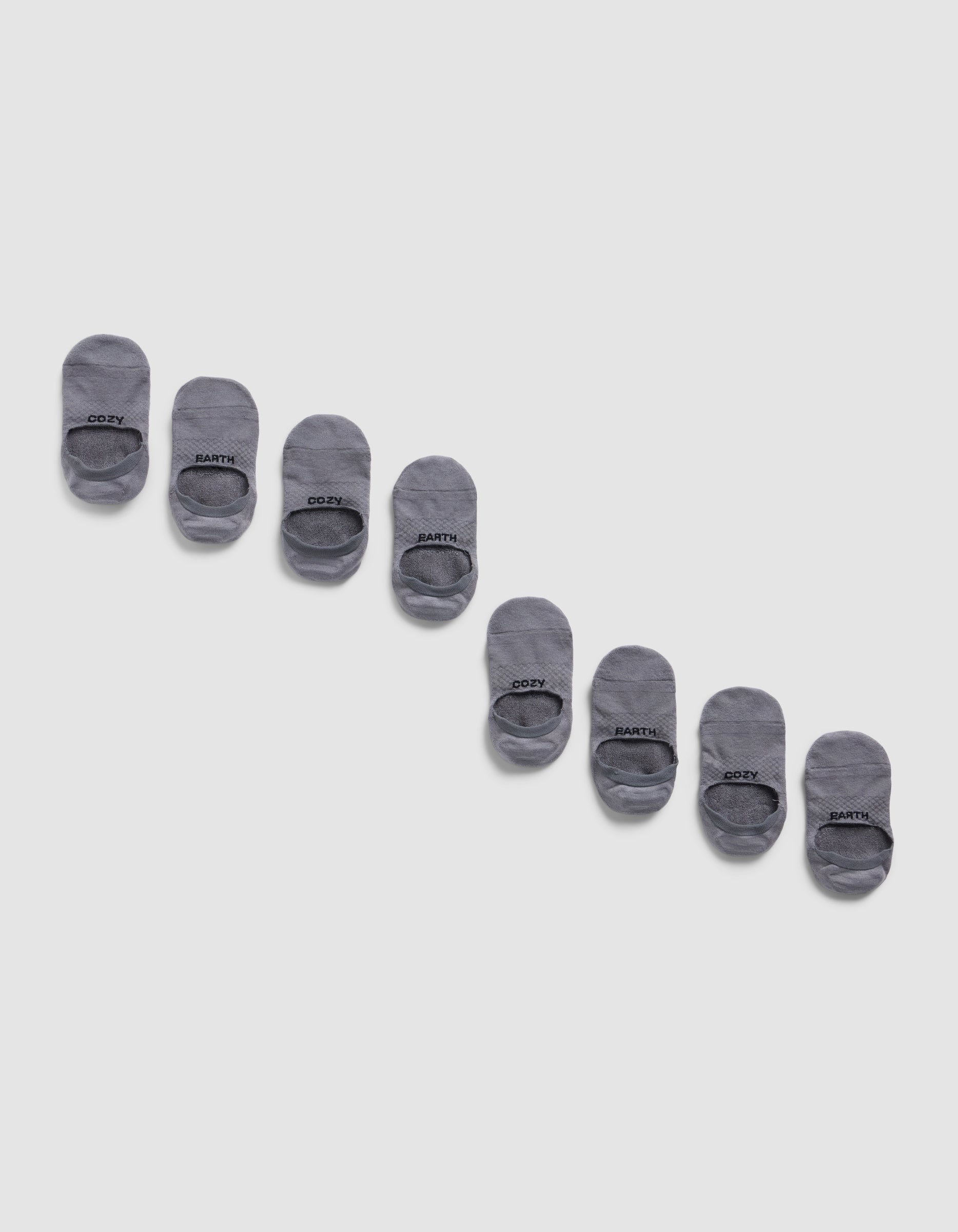 Eight pairs of Cozy Earth Essential No-Show Socks are displayed diagonally on a light gray background, neatly aligned in alternating pairs with black text near the toe.|Color:Stone