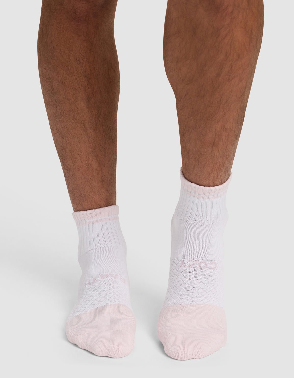 A person with bare legs is wearing Cozy Earth's Essential Quarter Sock - Last Chance in white with light pink toes, standing on a white background. 