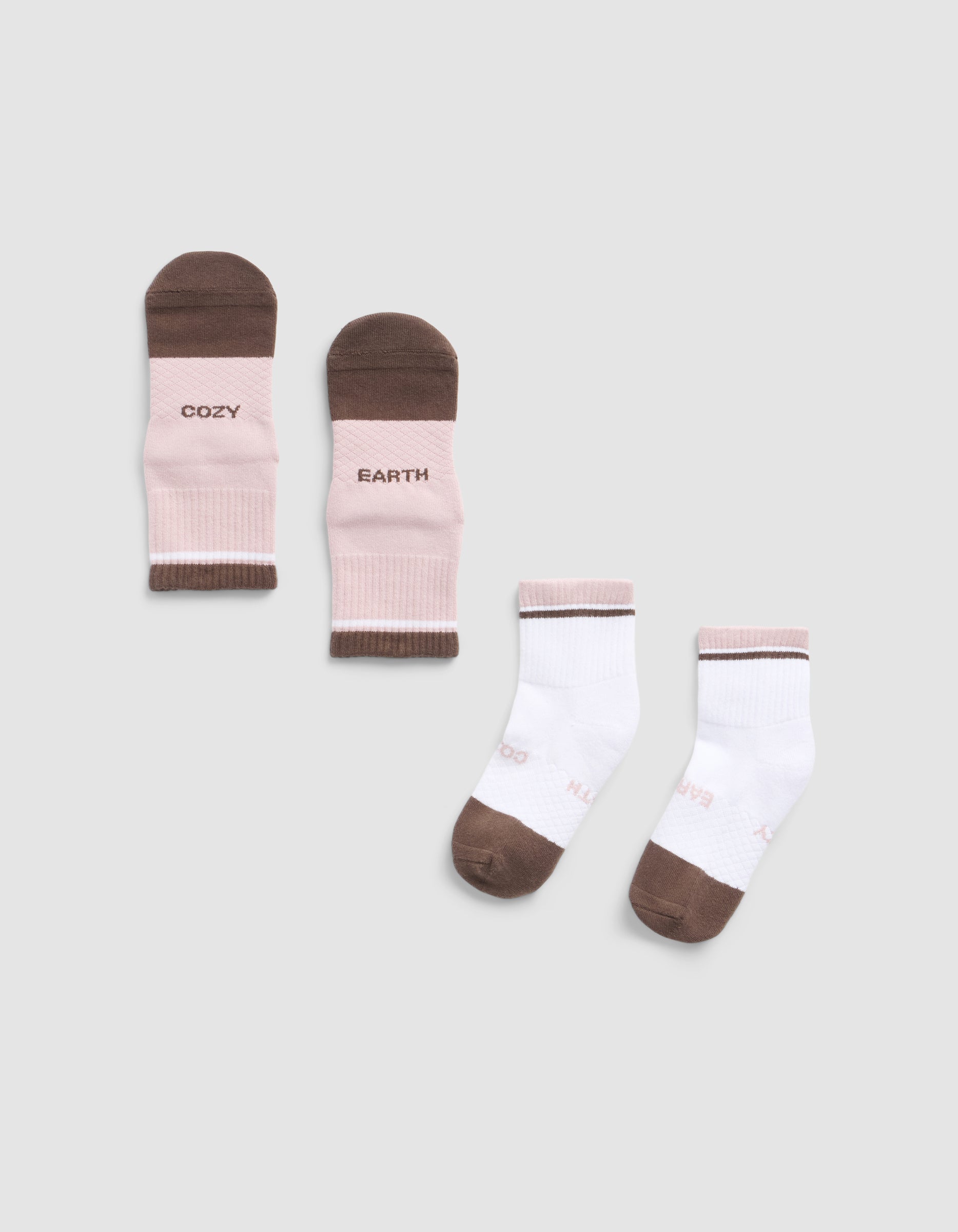 The Cozy Earth Essential Quarter Sock set includes two pairs: one pink and brown pair with "COZY" and "EARTH" text, and one white pair with brown toes, heels, and light pink accents. All are shown on a light grey background.|Color:Cedar