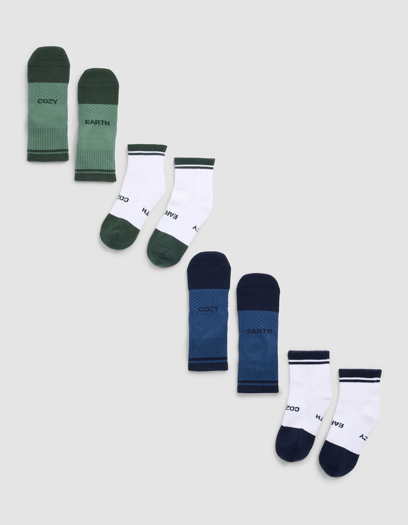 The Essential Quarter Sock 4-Pack by Cozy Earth features green, white, blue, and navy socks with "COZY" and "EARTH" on each pair, displayed diagonally on a light gray background. 