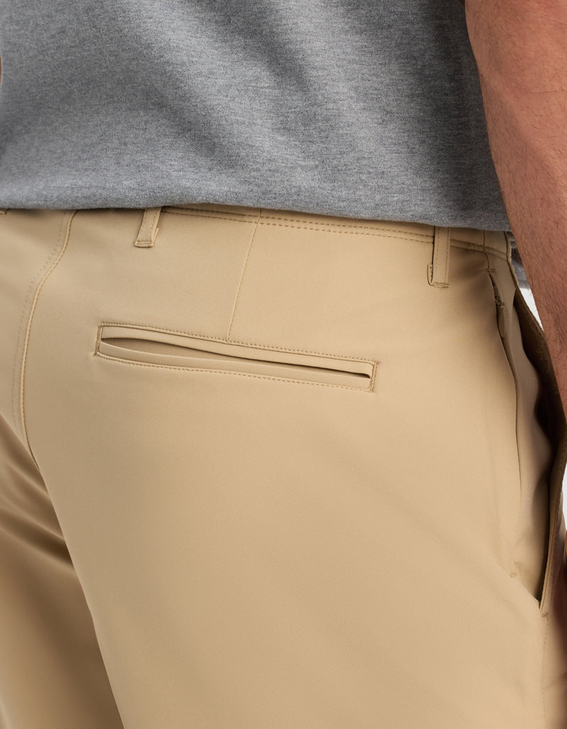 Close-up of a person wearing Cozy Earth Men's Everywhere Short in beige, featuring a back welt pocket, with a grey shirt; side and partial back view focuses on the waist and hip area.
