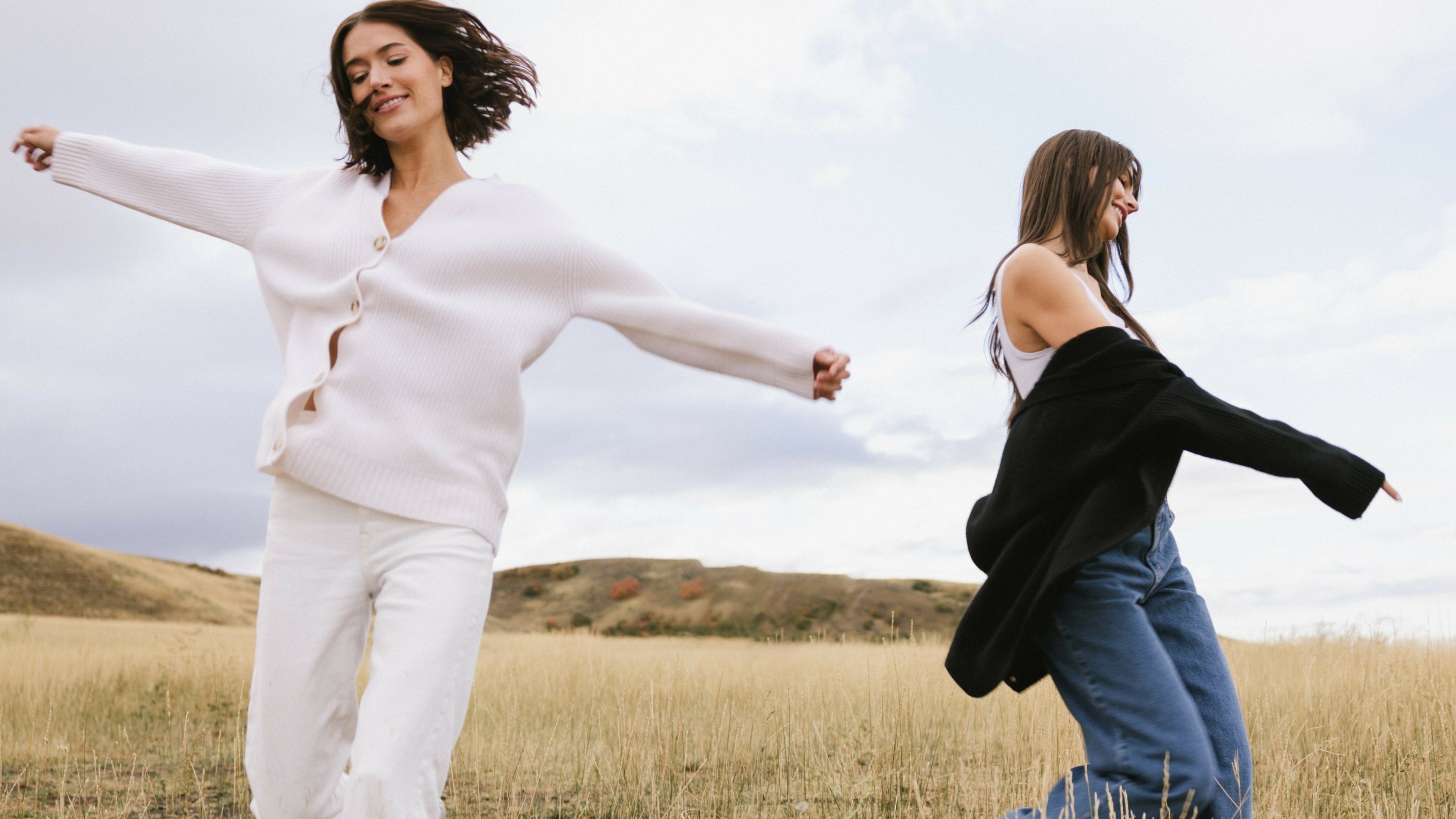 Two women running in a field with a clear sky
