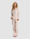 A woman with long blonde hair smiles and stands with her hands in her pockets, modeling the Cozy Earth Women's Farmhouse Long Sleeve Pajama Set in light pink plaid against a plain gray background.|Color:Quartz Plaid