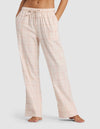 A woman models the Cozy Earth Women's Farmhouse Pajama Pant in light pink plaid, featuring a drawstring waist, while standing barefoot against a plain light background.|Color:Quartz Plaid