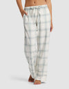 A woman wears Cozy Earth's Women's Farmhouse Pajama Pant—loose-fitting, light plaid with a drawstring waist and pockets—standing barefoot against a plain background.|Color:Wintergreen Plaid