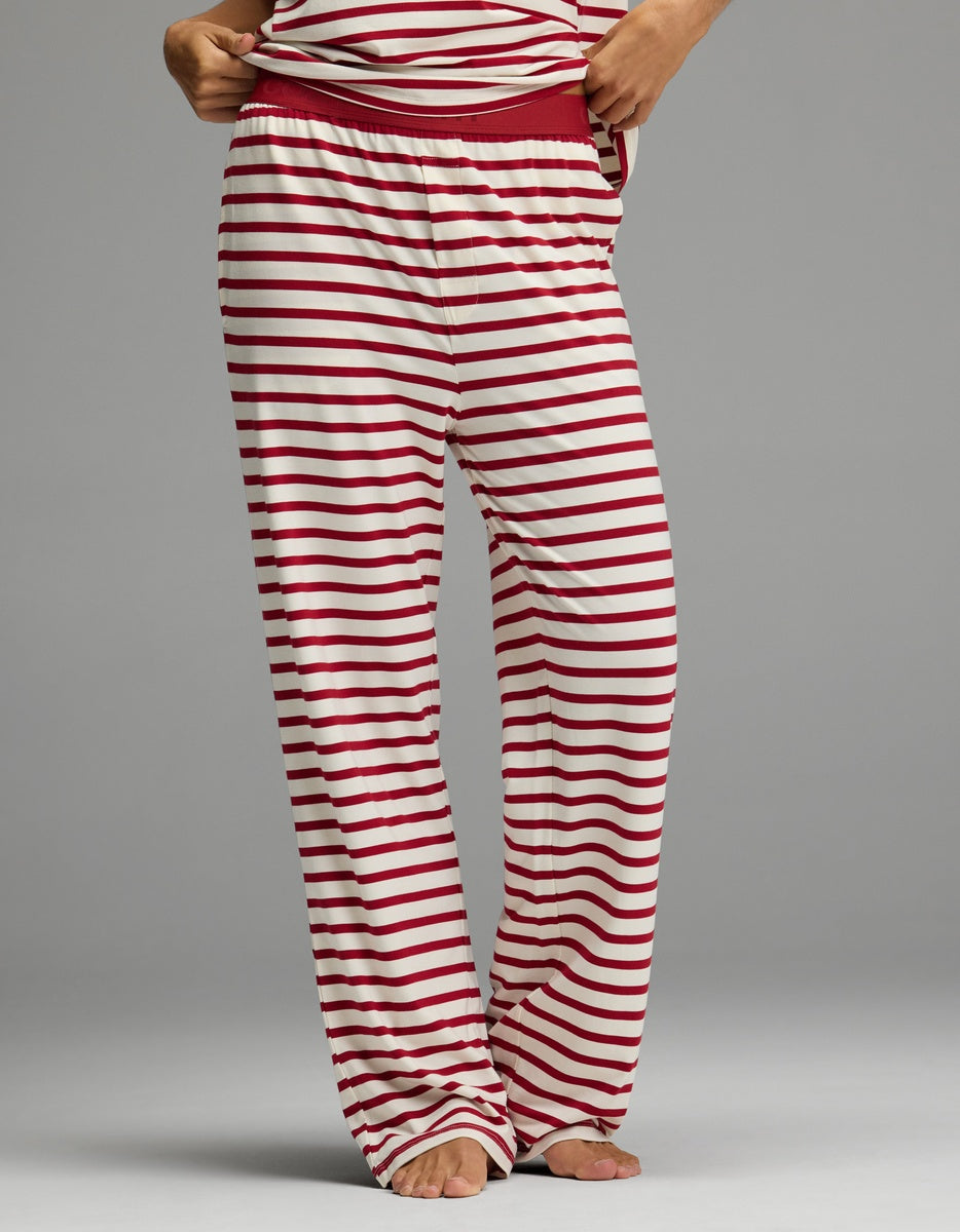 A person wearing Cozy Earth Women’s First Layer Pajama Pant featuring loose-fitting horizontal red and white stripes and a solid red elastic waistband.